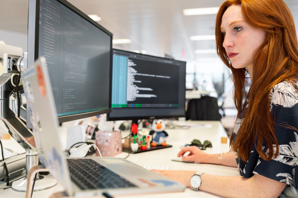 Developers working together at a desk with code on monitors